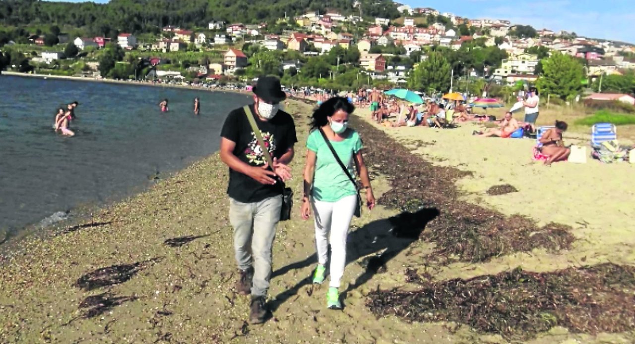 Roberto Villar y la bióloga de Ecoloxistas en Acción recorriendo la playa de Cesantes que cuenta ya con la &#34;barrera&#34; natural que crean las algas.