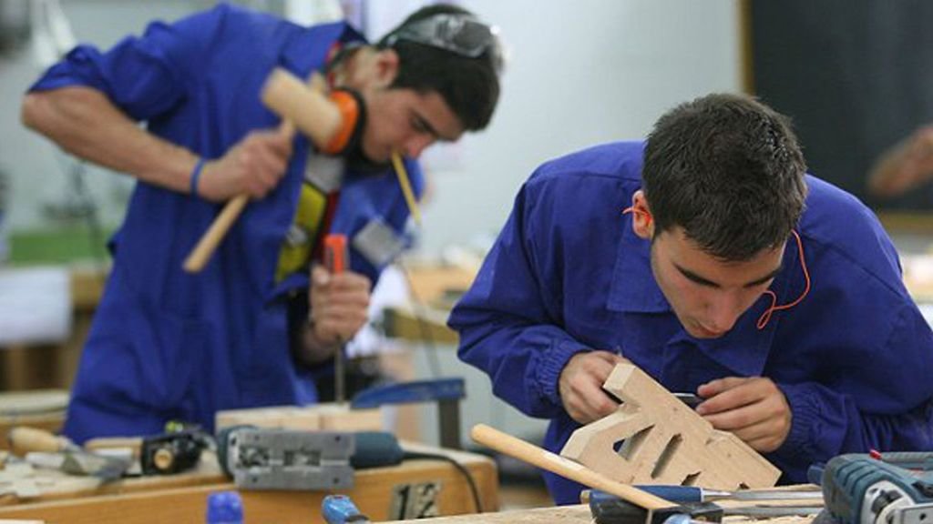 Dos jóvenes trabajan en un taller de carpintería.