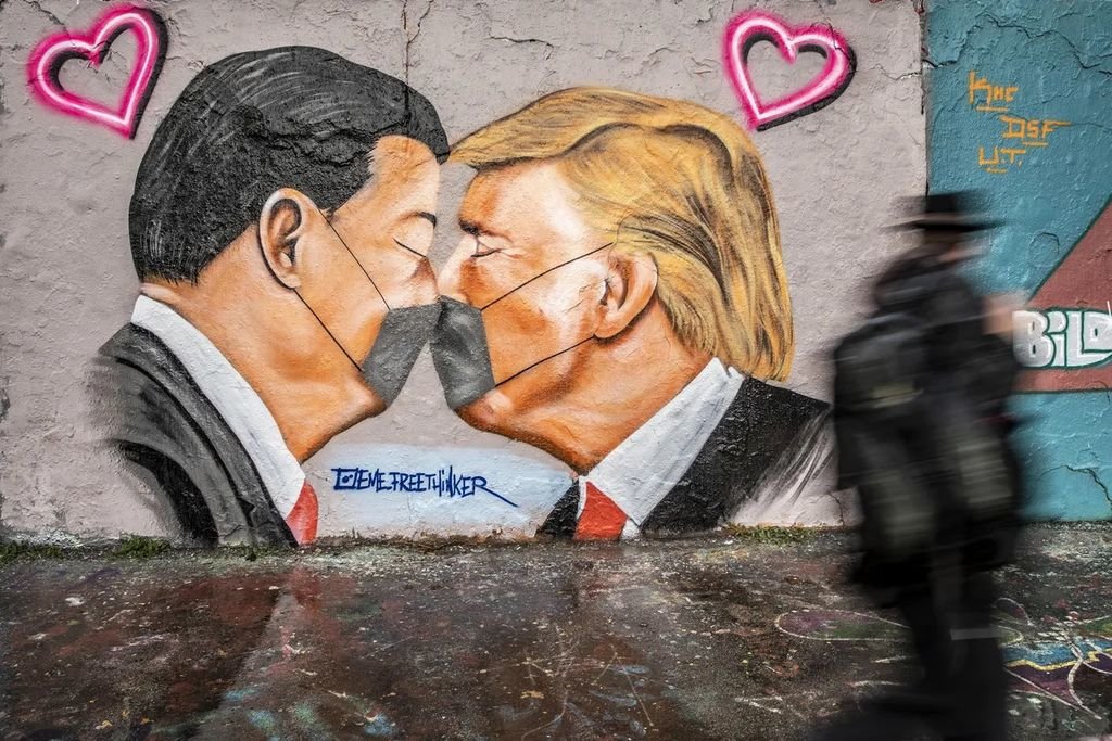 Un hombre camina ante un mural del presidente Donald Trump y el presidente Xi Jinping en Berlín.