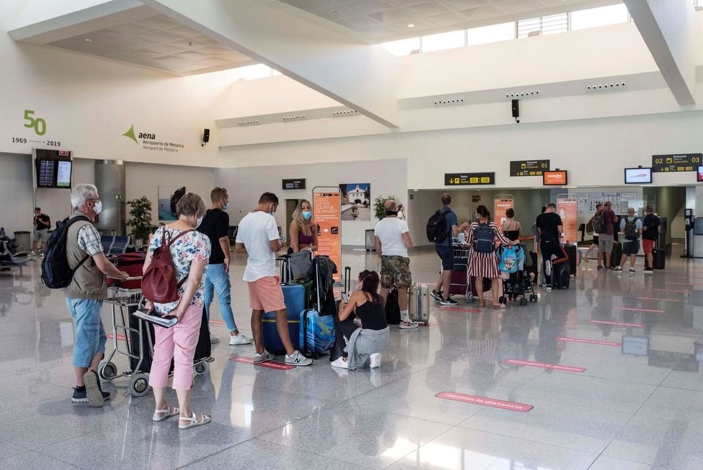 Un grupo de viajeros hacen cola para facturar en el aeropuerto de Mahón, en Menorca.