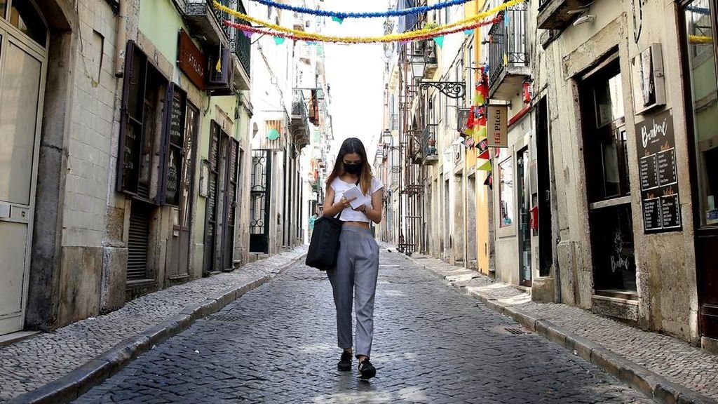 Una mujer con mascarilla pasea por una calle de Lisboa.