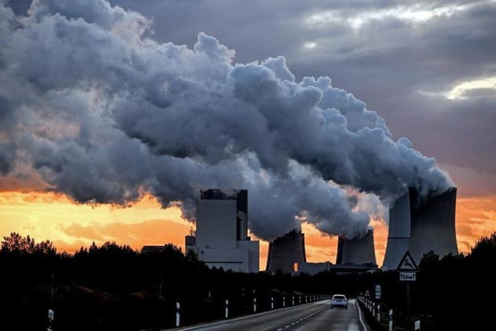 Una fábrica desprende gases contaminantes en las inmediaciones de una carretera comarcal.