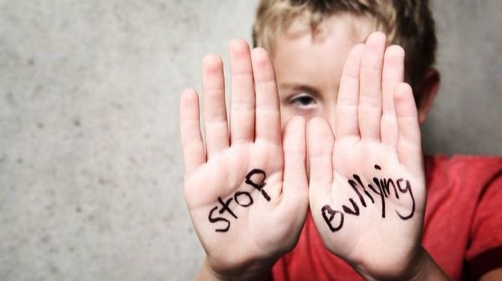 Imagen de un alumno con las palmas de las manos escritas con la frase: &#34;Stop Bullying!&#34; (¡Fin al acoso!).