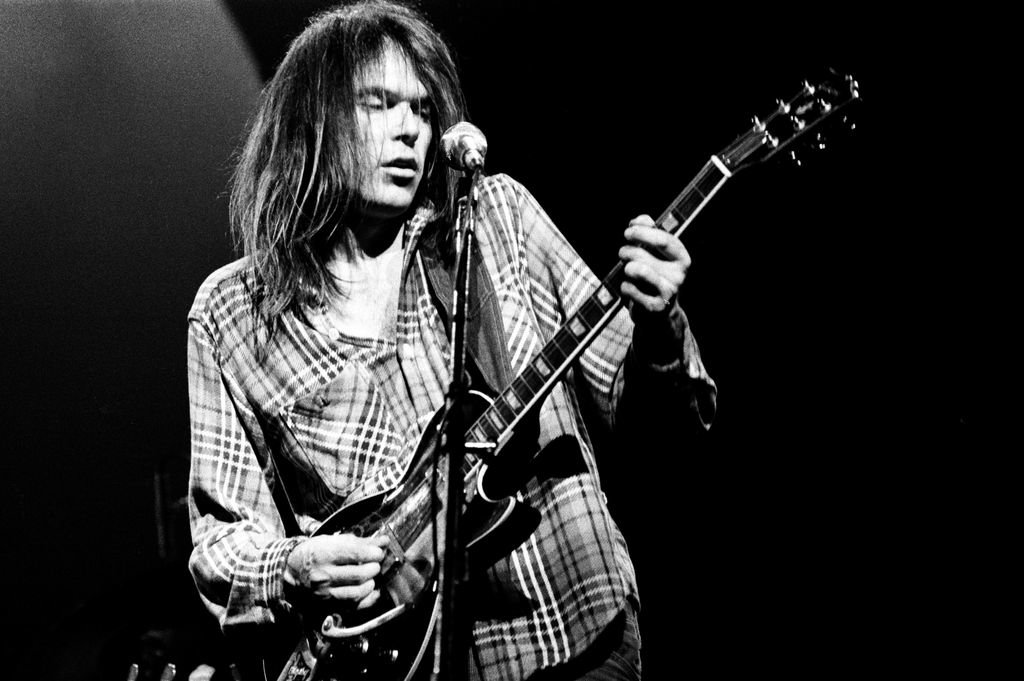 Neil Young tocando la guitarra eléctrica durante uno de sus conciertos.