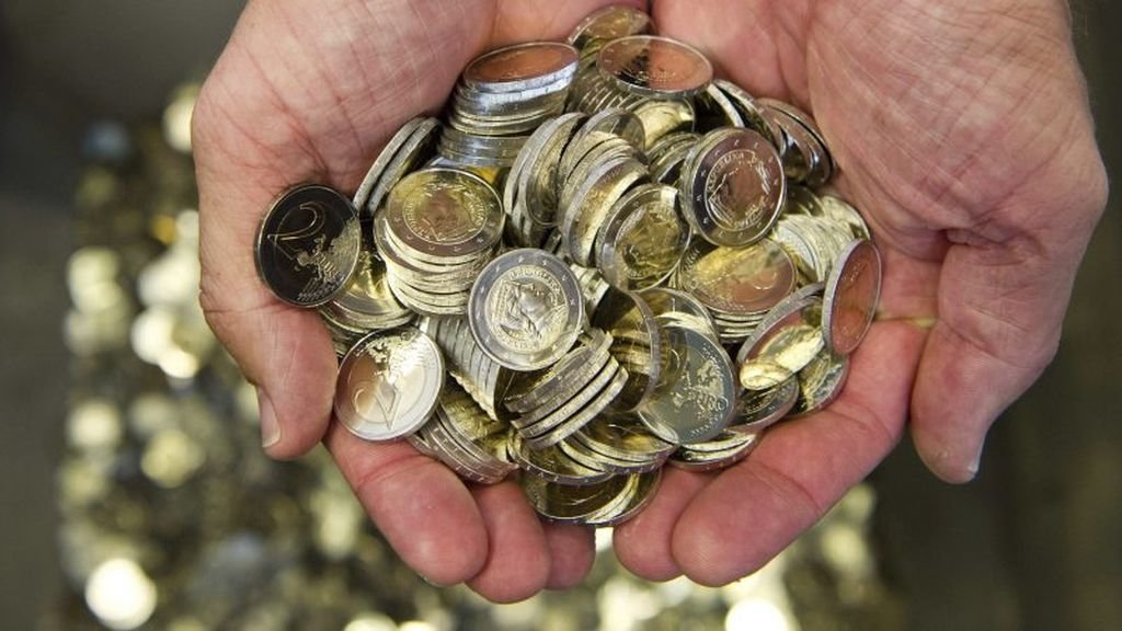 Un hombre sostiene varias monedas de euro.