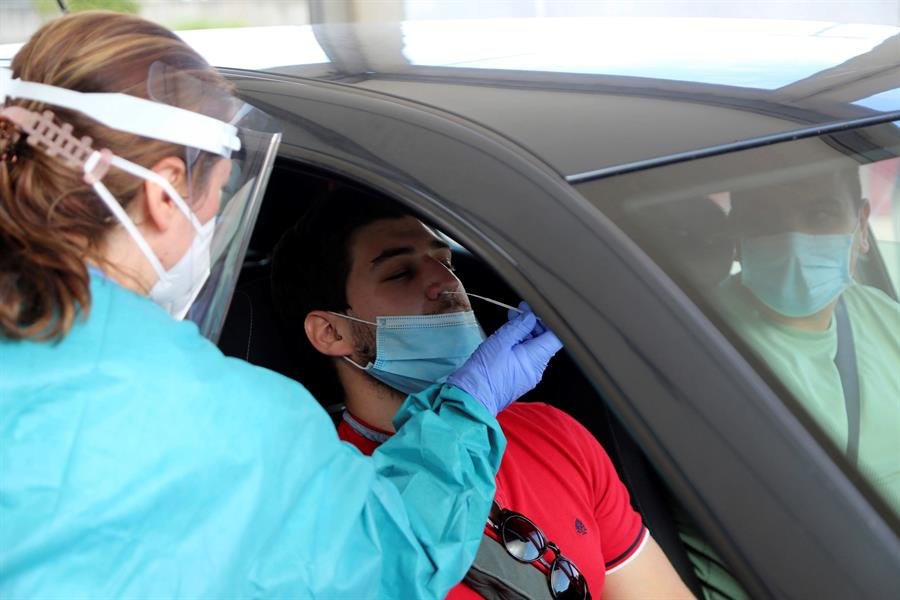 Personal sanitario realiza una prueba de PCR a un hombre desde automóvil en el Hospital Alvaro Cunqueiro de Vigo.