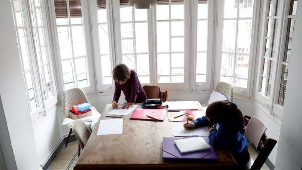Dos niños hacen los deberes en su casa.