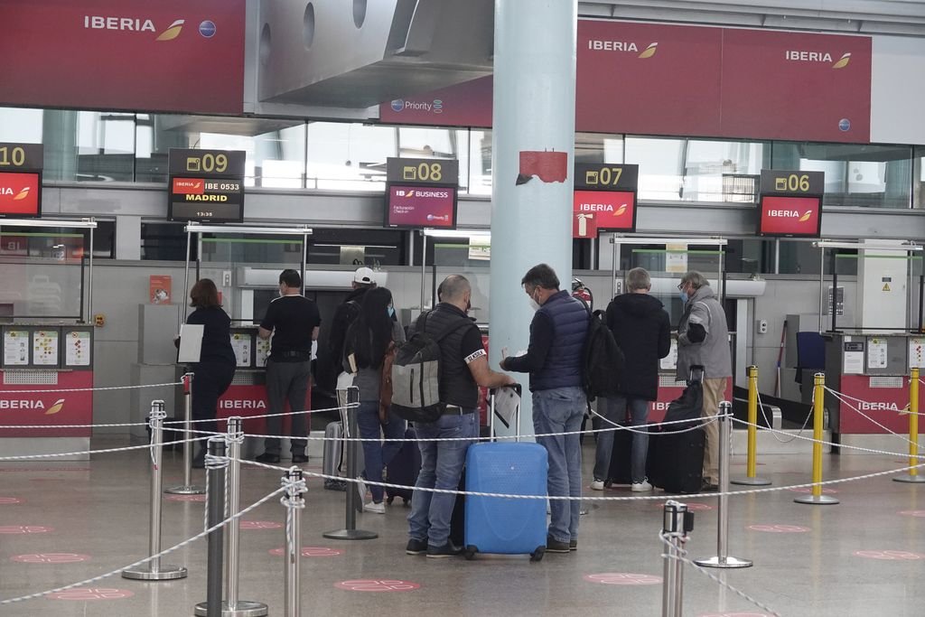 Pasajeros del vuelo Vigo-Madrid que opera la compañía Iberia, en la cola de facturación guardando las distancias de seguridad obligatorias.