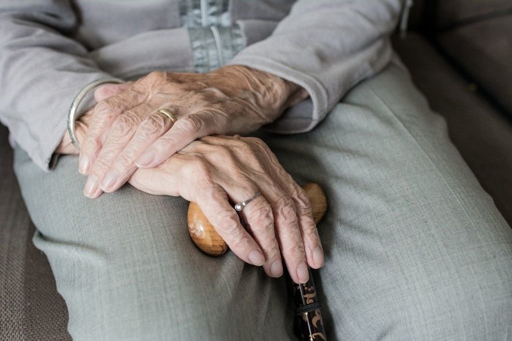 Una persona dependiente de avanzada edad sostiene un bastón.