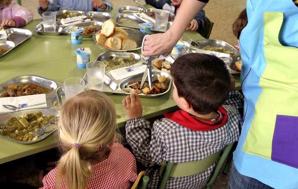 Niños, con su menú, en un comedor escolar.