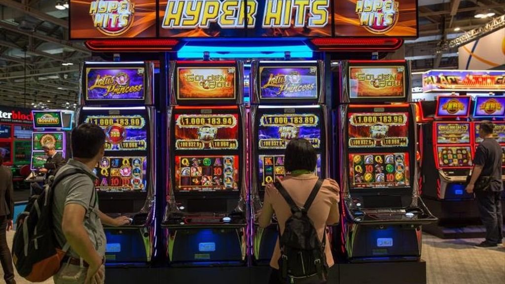 Dos personas apuestan en las máquinas tragaperras de un casino.