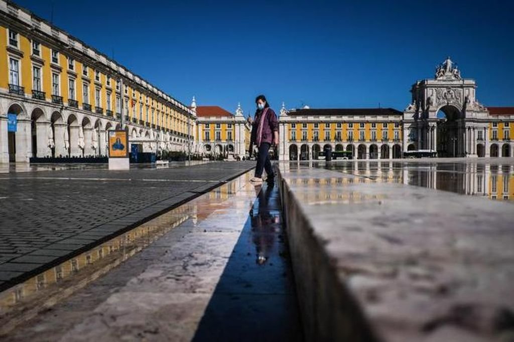 Una mujer con mascarilla camina por la plaza del Comercio de Lisboa, Portugal.