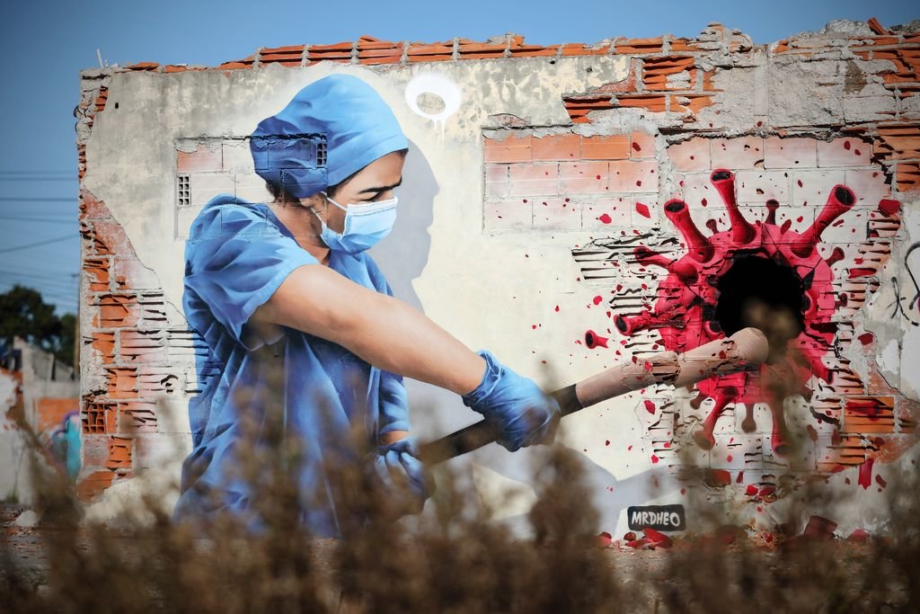 Un grafiti del artista callejero MrDheo representa a una sanitaria golpeando al covid-19, en Vila Nova de Gaia, Portugal.
