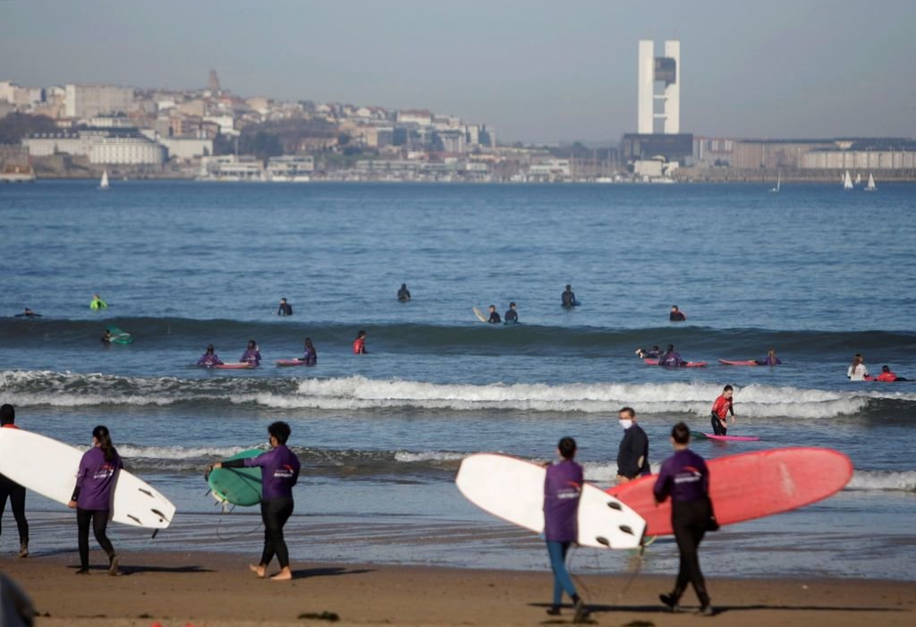 Un numeroso grupo de jóvenes practica el surf en la playa coruñesa de Riazor.