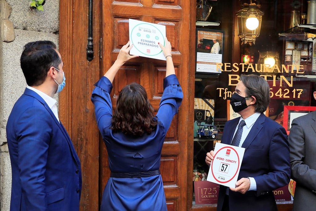 Ayuso coloca un cartel en un restaurante de Madrid.