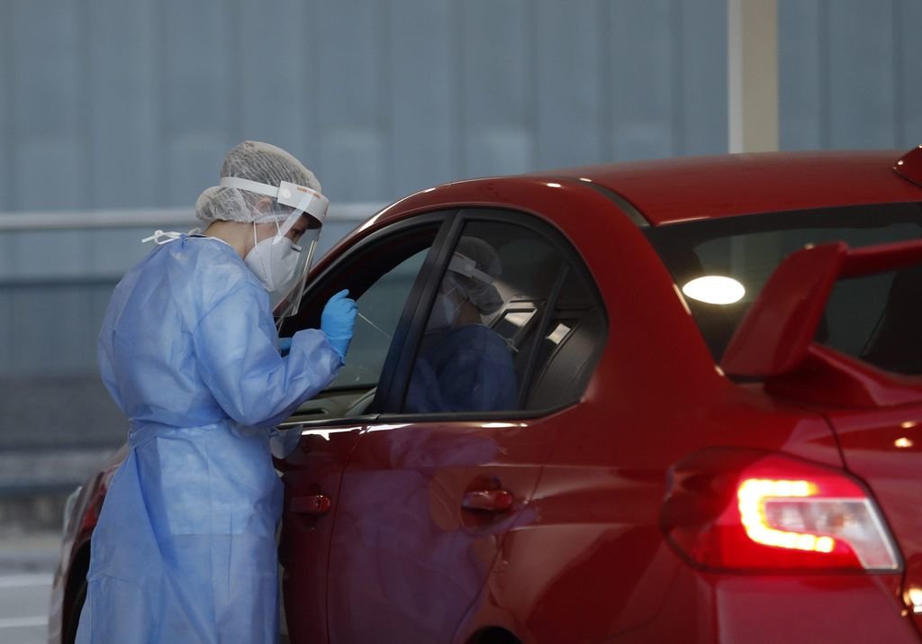 Una enfermera realiza una prueba de PCR a una persona en el interior de un coche.