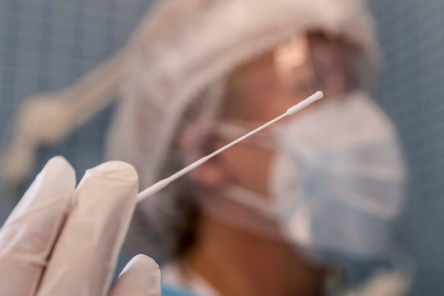 Una enfermera sostiene un bastoncillo mientras realiza una prueba PCR.