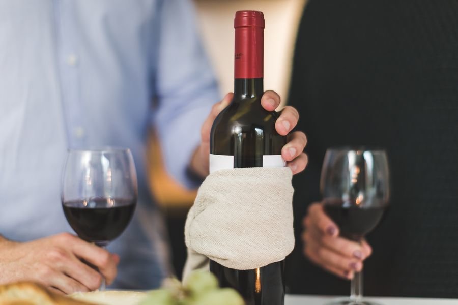 Una persona sirve dos copas de vino, uno de los productos más afectados por los aranceles de EEUU.