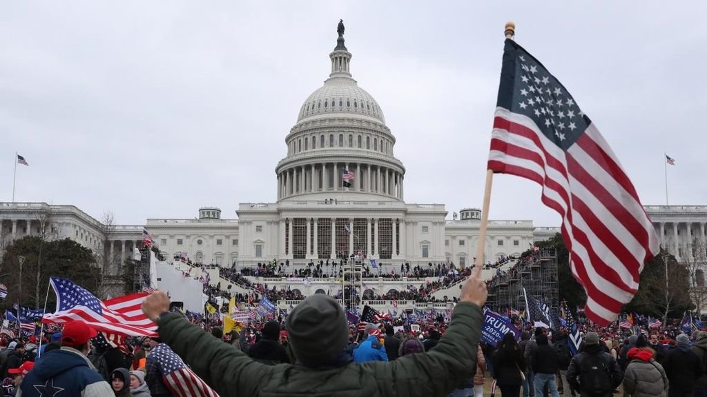 Un seguidor de Donald Trump sostiene la bandera de EEUU durante el asalto al Capitolio el 6 de enero.