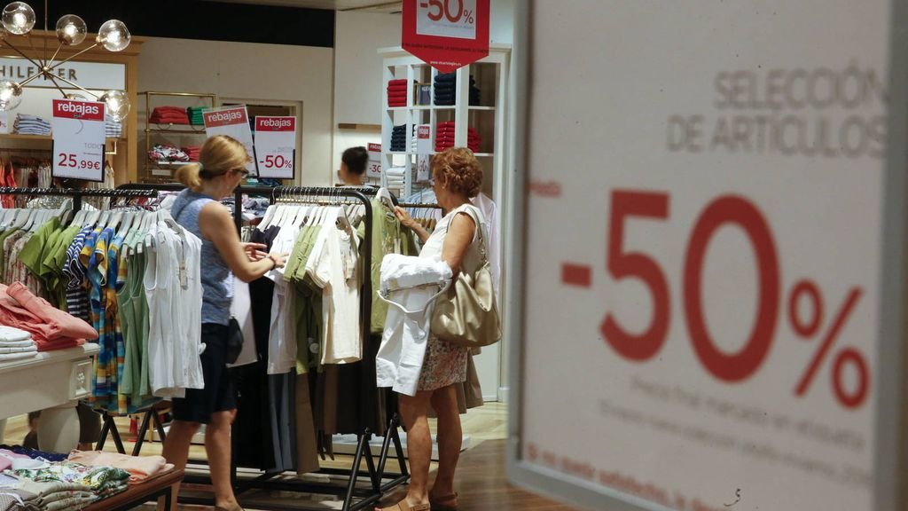 Unas mujeres rebuscan entre las prendas que se ofertan en las rebajas en una tienda textil.