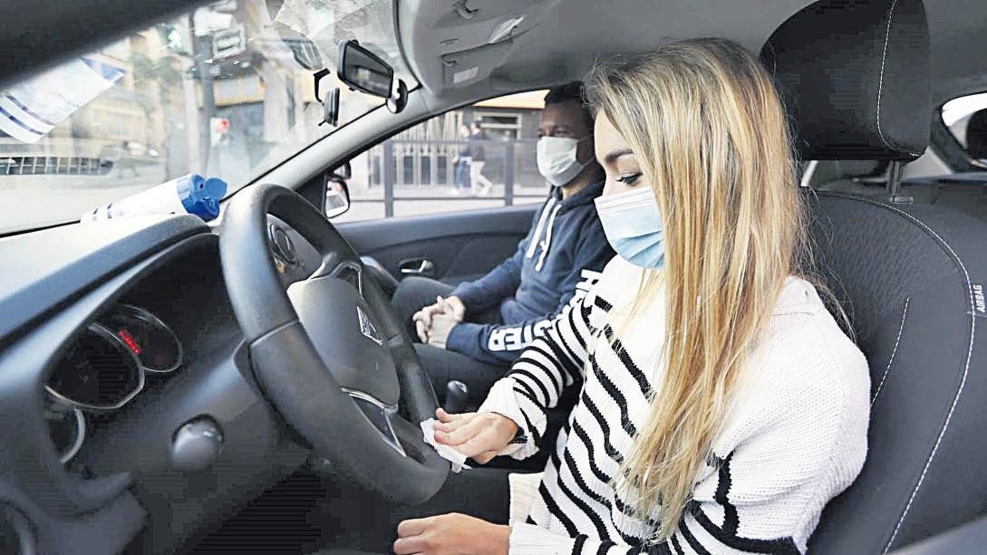 Una alumna de una autoescuela, junto a su profesor, desinfecta el volante del coche de prácticas.