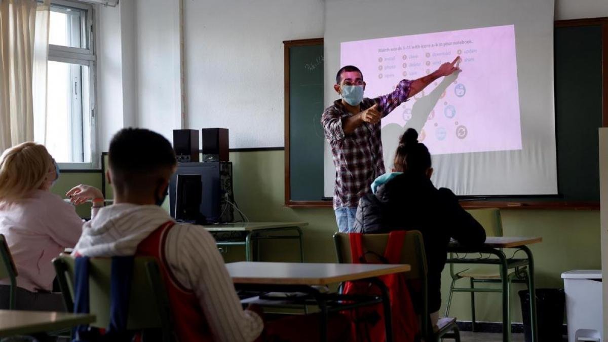 Una alumna atiende a las explicaciones del profesor en un aula.