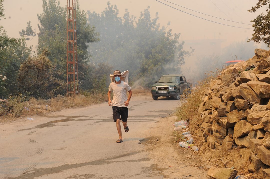 Un argelino corre por un camino dejando atrás uno de los incendios porducidos en el norte de su país.
