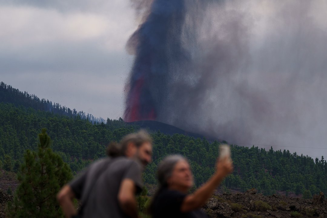 Dos personas se hacen un selfi ante la impresionante columna de humo y fuego de la Cumbre Vieja.