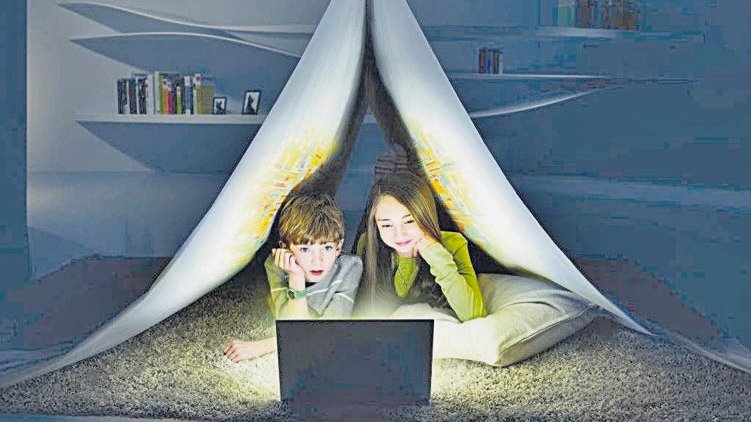 Dos niños con el ordenador en su habitación durante el horario nocturno.