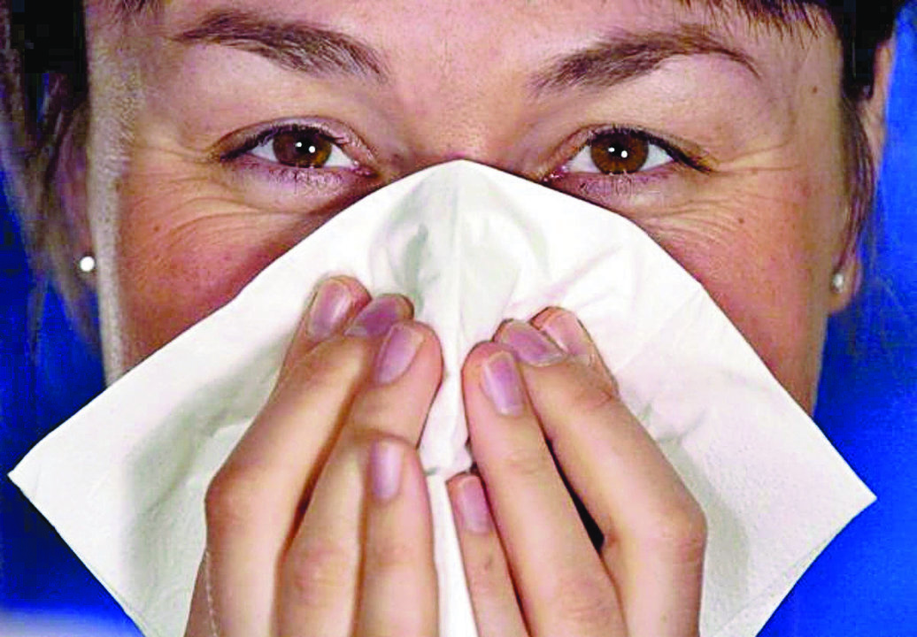 Una mujer se suena la nariz con un pañuelo de papel.