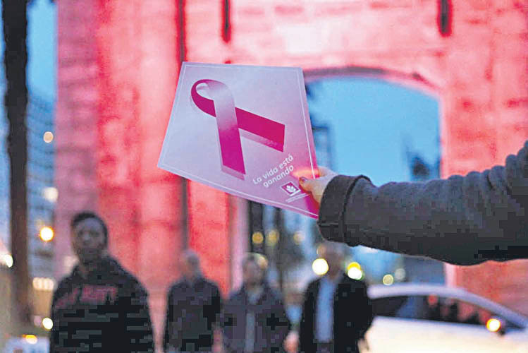 Una mujer sostiene un panfleto en apoyo a las persoans que sufren cáncer de mama.
