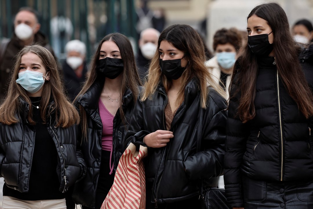 Un grupo de jóvenes camina por una calle de Valencia cubriendo sus narices y bocas con mascarillas.