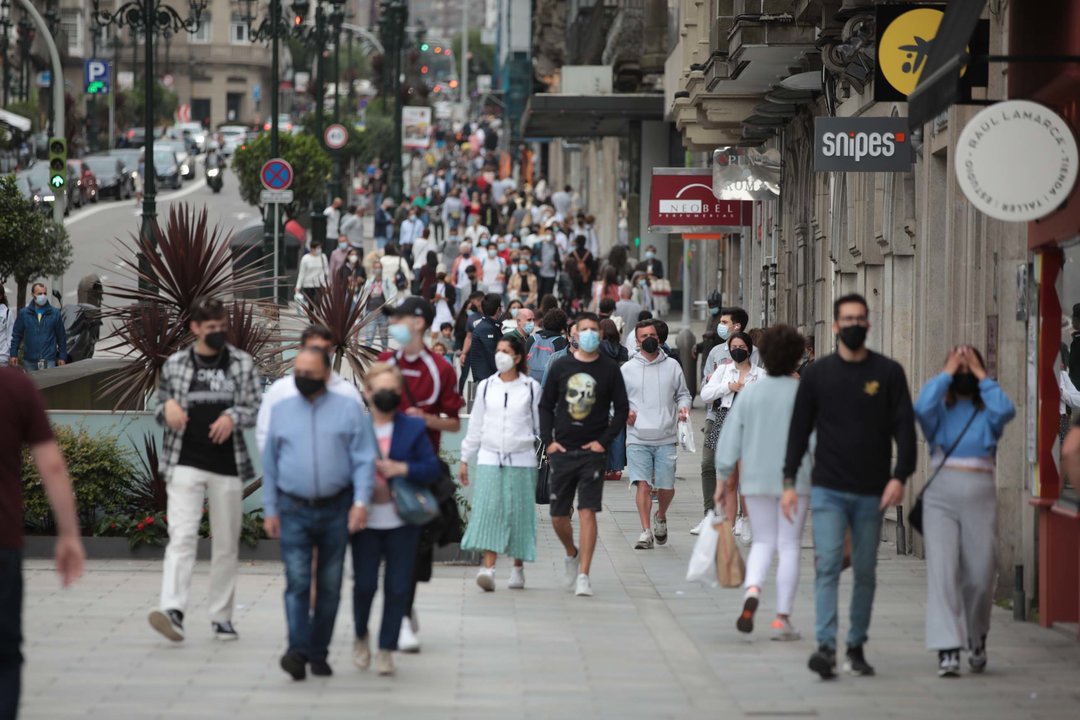 Personas caminan por el centro de Vigo con la mascarilla puesta.
