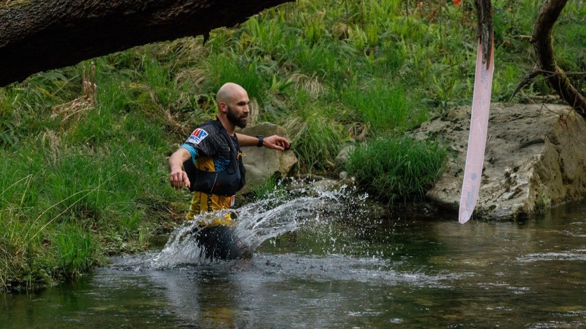 Uno de los participantes cruza un río en el transcurso del Trail de Oia.