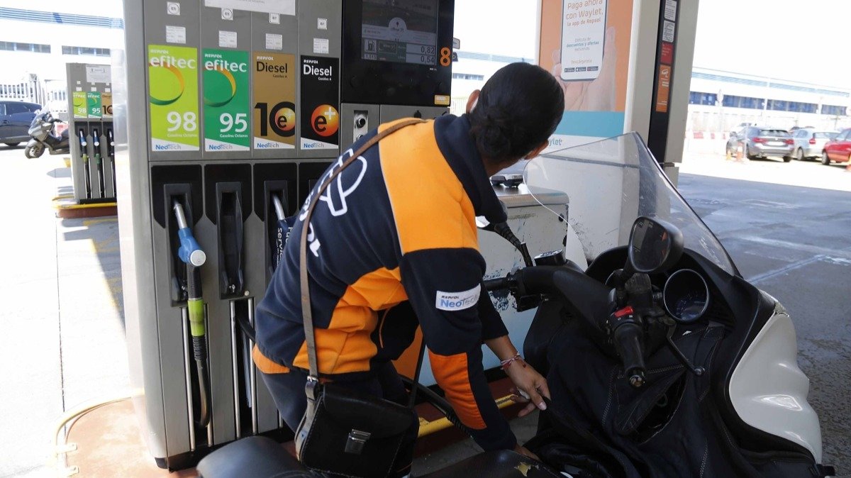 Un empleado llena el depósico de una motocicleta en una gasolinera de Vigo.