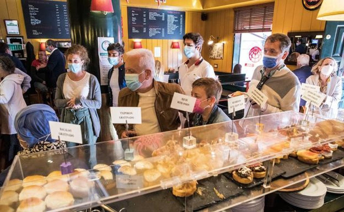 Un grupo de personas con mascarilla en una pastelería en Madrid.