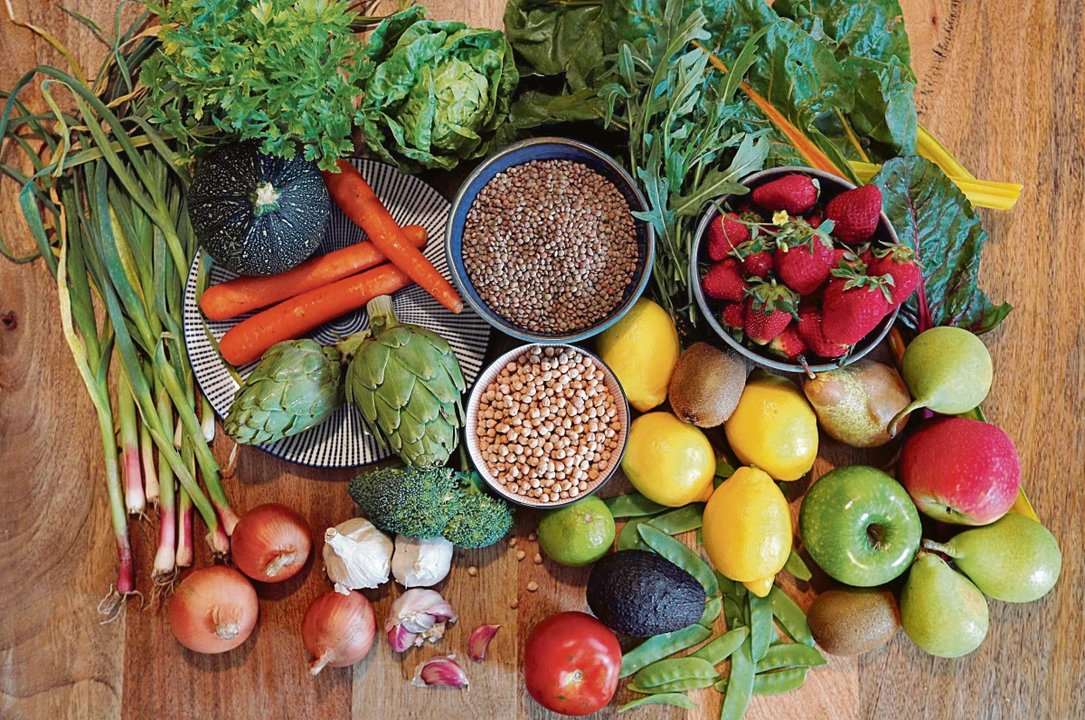 Una mesa sobre la que reposan frutas, verduras y legumbres.