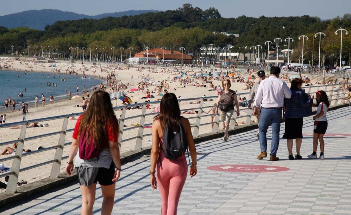 Personas caminando por el paseo de Samil, tomando el sol en la arena y disfrutando de un refrescante baño en el mar.