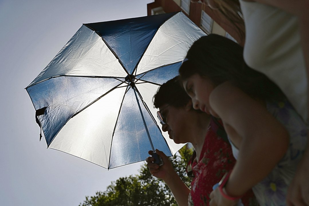 Una mujer y su hija se cubren del sol con un paraguas en Madrid este sábado.