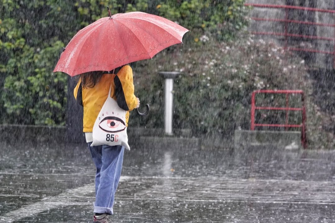 Una mujer se tapa de la lluvia, este lunes. // Vicente Alonso