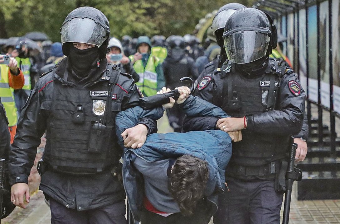Un grupo de antidisturbios se llevan detenido a un joven que protestaba contra la movilización.