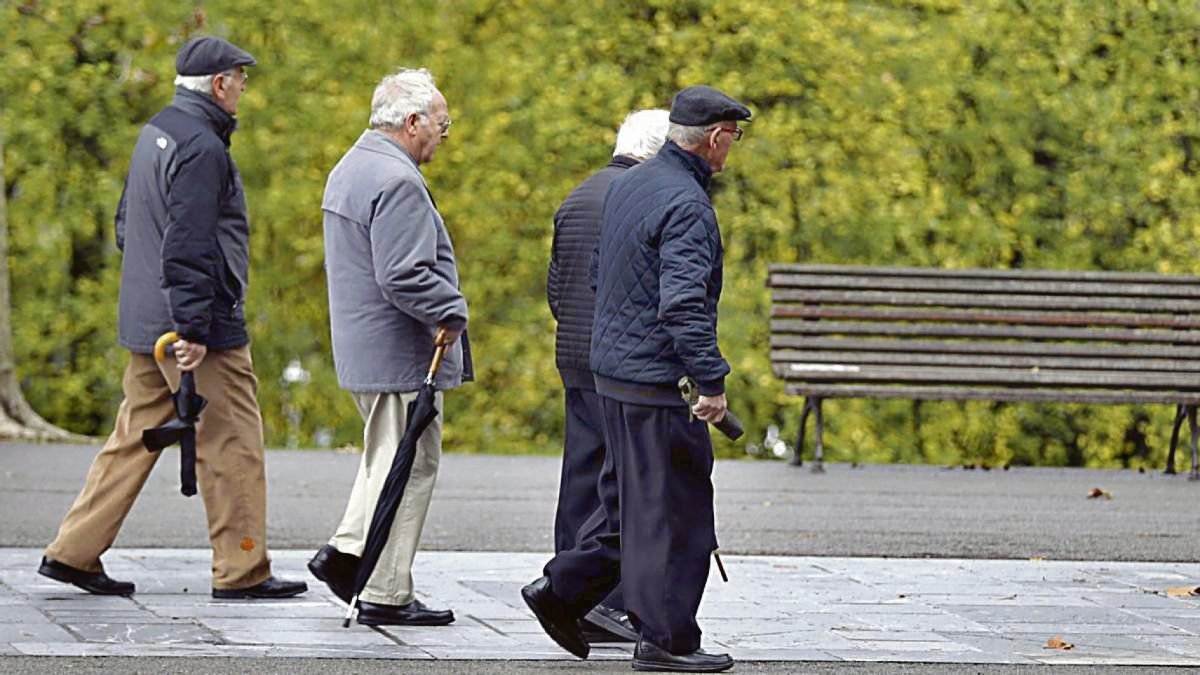 Pensionistas y jubilados pasean en un parque.