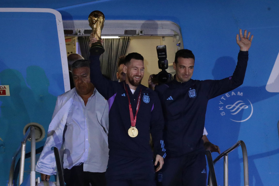 Lionel Messi de la selección argentina de fútbol saluda con el trofeo del Mundial de Fútbol Qatar 2022 junto al seleccionador Lionel Scaloni (d) a su llegada hoy, al Aeropuerto Internacional de Ezeiza a unos 22km de Buenos Aires (Argentina)