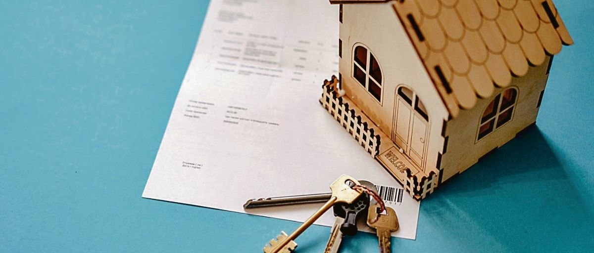 Un contrato de hipoteca, junto a las llaves de la casa y una maqueta de la misma.