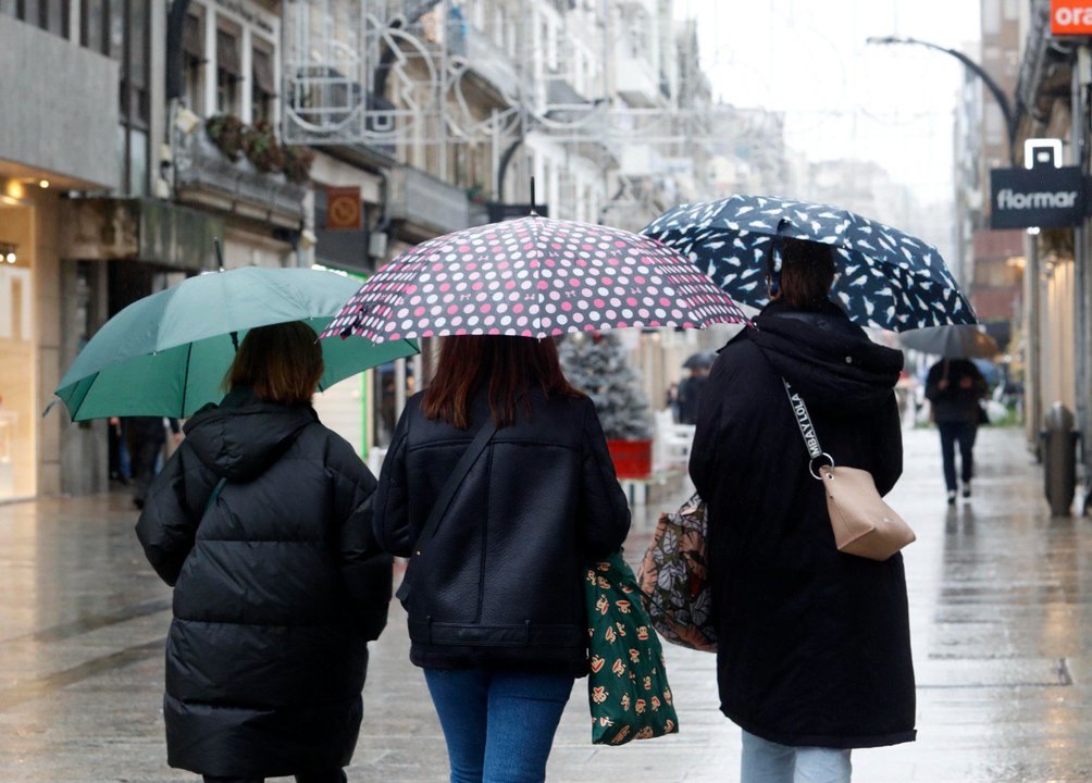 Tres mujeres se tapan de la lluvia con paraguas en Vigo. // J.V. Landín