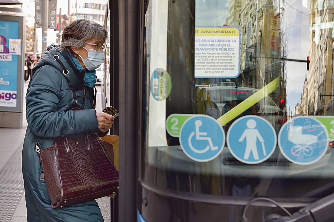 Una persona con mascarilla se sube en un autobús, en Madrid.