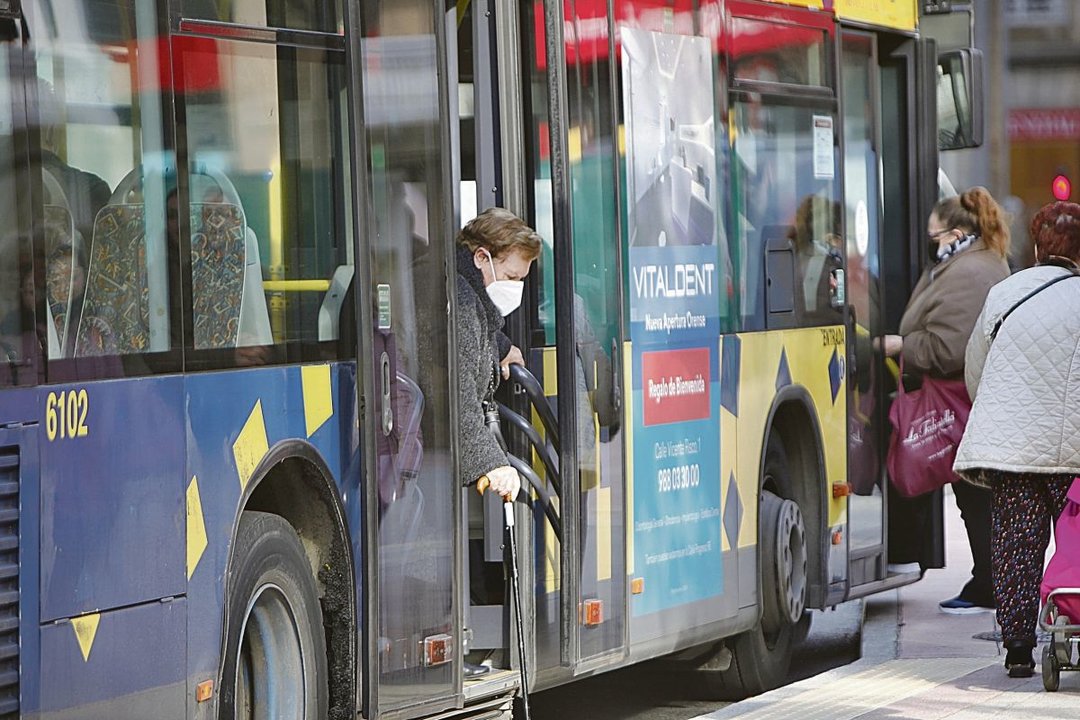 Varias personas suben y bajan de un autobús urbano en Ourense portando la mascarilla.