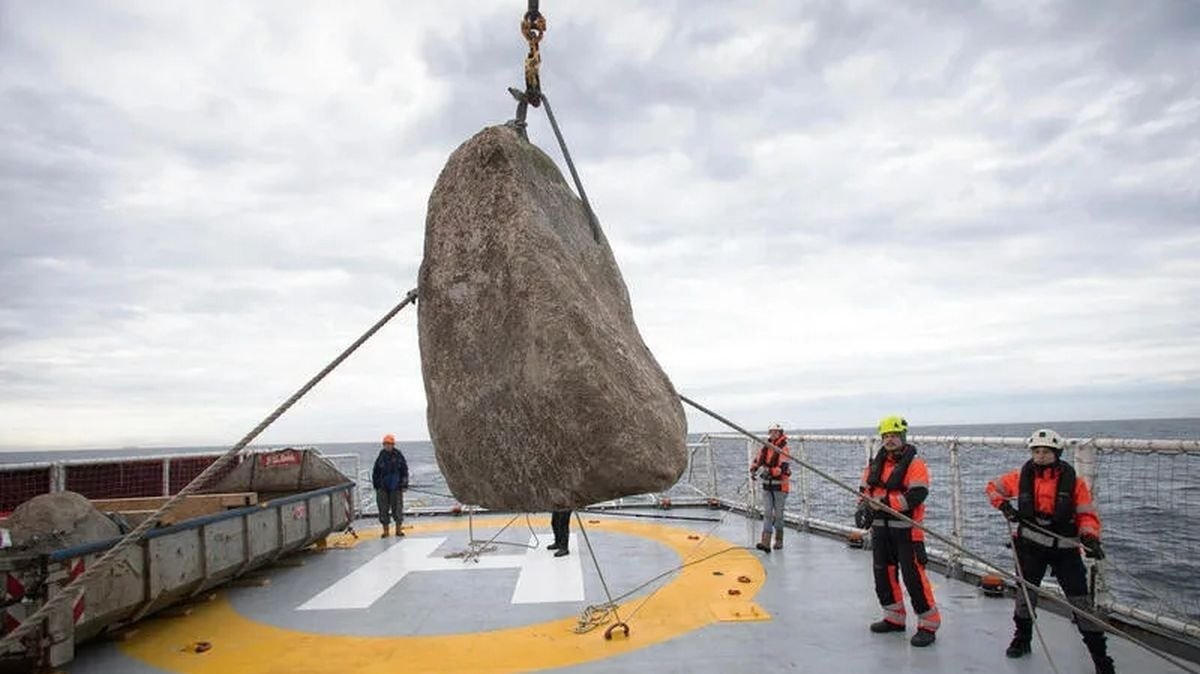 Ecologistas de Greenpeace lanzando una roca de gran tamaño al mar.