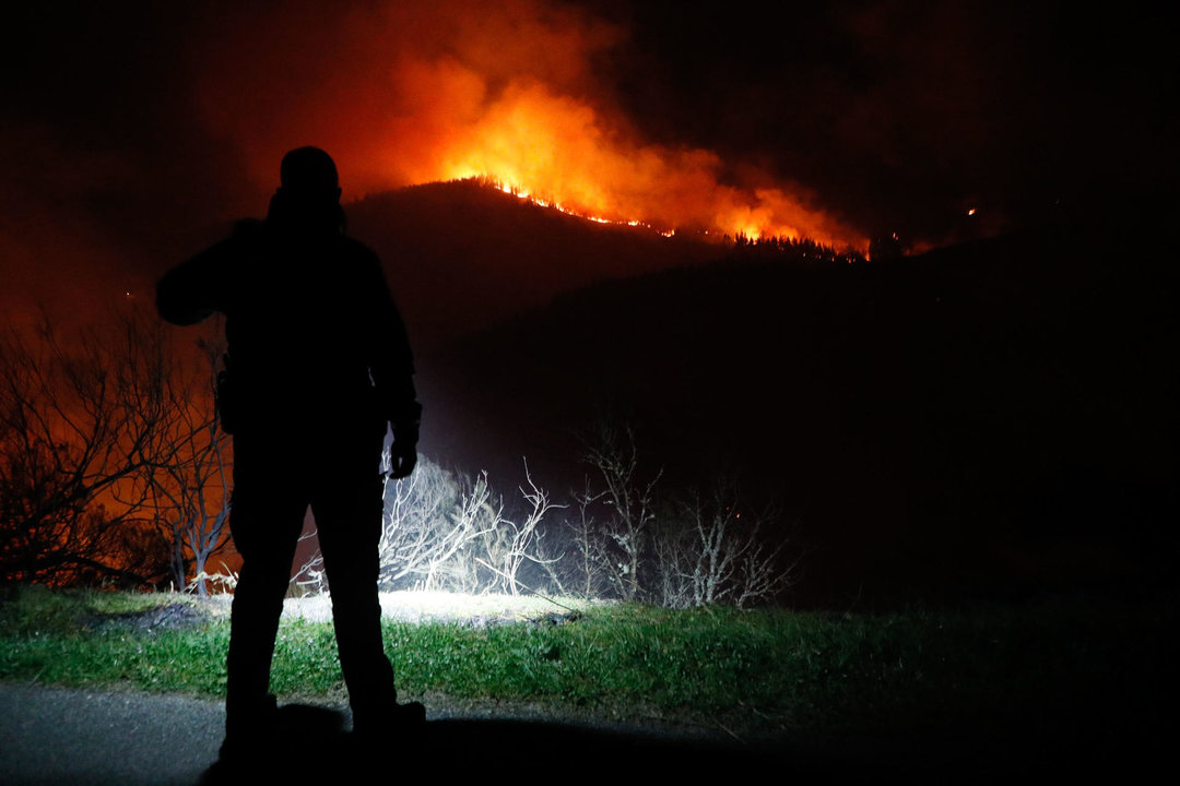 Un Guardia Civil observa las llamas en el monte en Cortevella, Lugo. // EFE