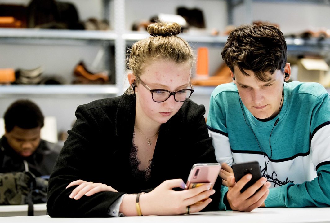 Estudiantes prestan atención a sus teléfonos móviles, en una fotografía de archivo. // EFE